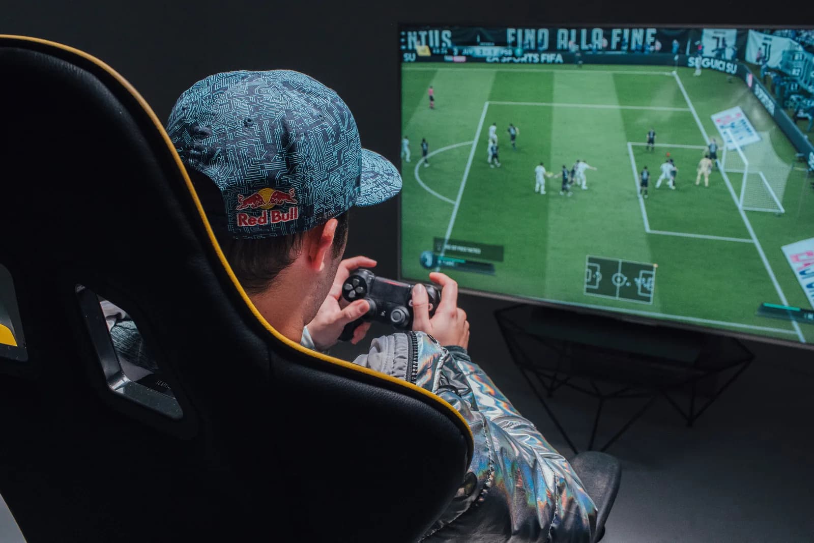 A player on a PlayStation controller in front of EA SPORTS FC